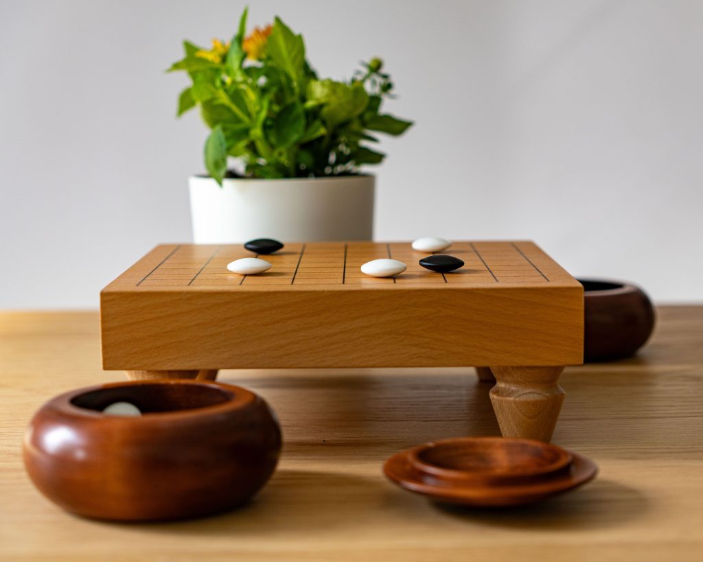 Elegant wooden Go board setup with game pieces and a lush green plant, perfect for mindfulness and strategic play.